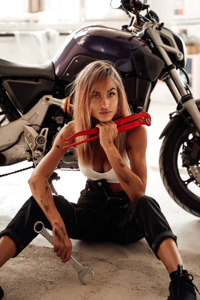 Яркий гараж и сидящая девушка со спортивным велосипедом внутри — стоковое фото