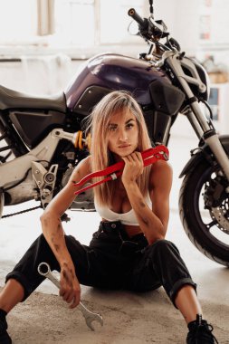 Elinde bazı aletler olan güzel sarışın bir kızla modern bir motosiklet.