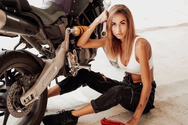 Γκαράζ σε εσωτερικούς χώρους και χαριτωμένο κορίτσι με προσαρμοσμένη μοτοσικλέτα — Φωτογραφία Αρχείου