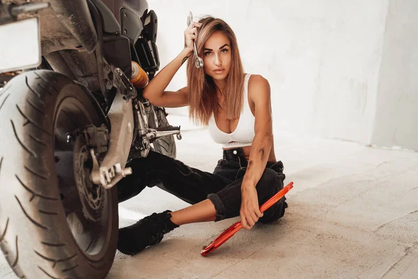 Приваблива дівчина в бруді, що крутиться біля спортивного мотоцикла — стокове фото