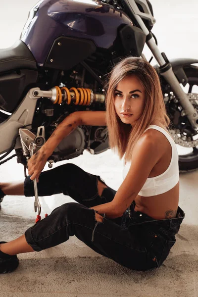 Ein modernes Sportmotorrad mit netten blonden Mädchen mit ein paar Werkzeugen an den Händen — Stockfoto