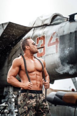 Sabit savaş uçağının yanında sigara içen modaya uygun bir ordu.