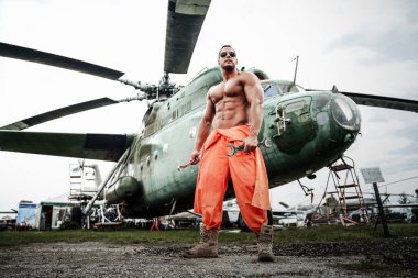 Havaalanında güçlü vücut geliştirici ve Sovyet helikopteri var.