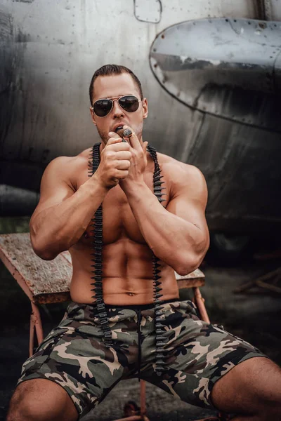 Crashed airplane and muscular military which smoking cigar — Stock Photo, Image