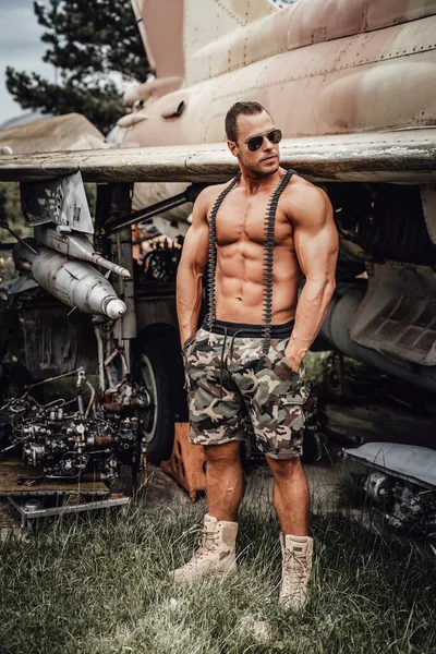 Homme militaire fort près d'un avion stationnaire de guerre — Photo