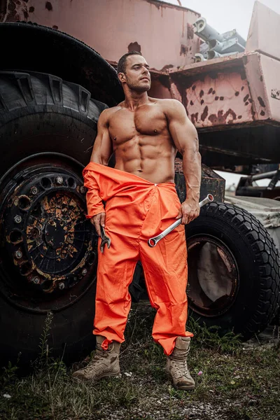 Naked guy holding wrench with abandoned machine behind — Stock Photo, Image