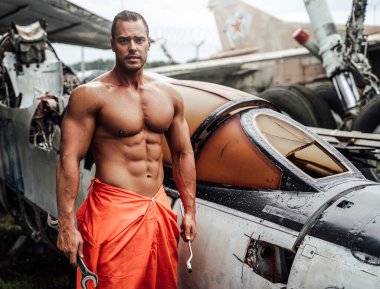 Gündüz vakti düşen uçağın yanında duran vücut geliştirici.