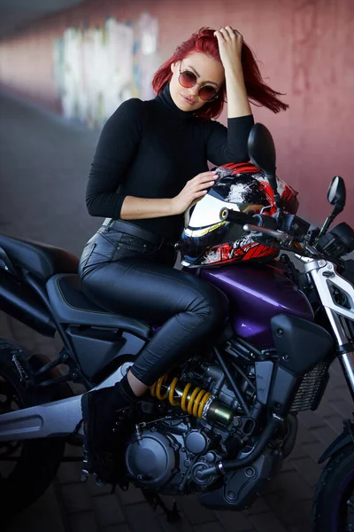 Современный мотоцикл и женщина-байкер с рыжими волосами — стоковое фото