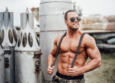 Güler yüzlü bronz tenli asker eski uçakların cephanesini koruyor.