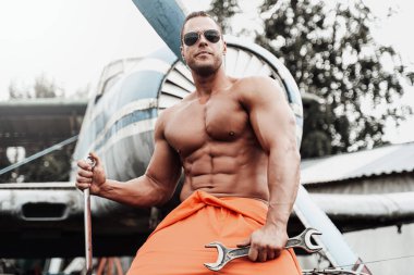 Teknisyen sporcu, eski uçağın yanındaki motorda oturuyor.