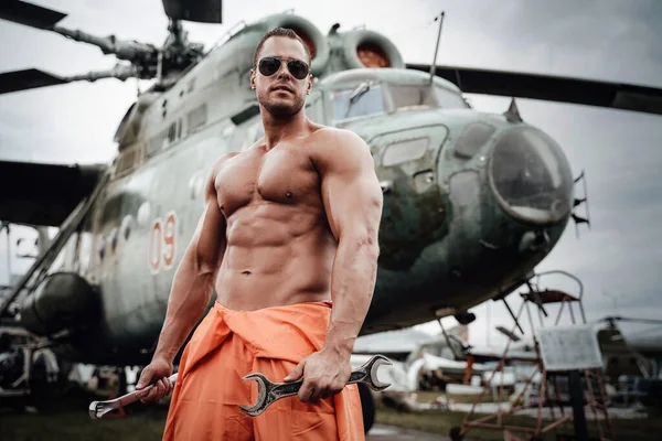 Havaalanında askeri teknisyen ve Sovyet savaş helikopteri.