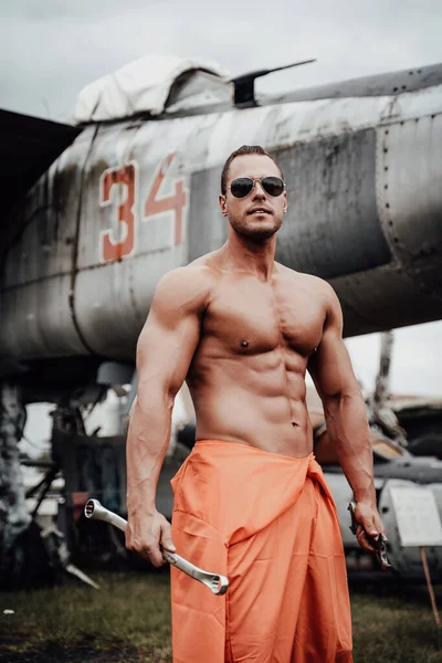 Attraente bodybuilder che rimane in aeroporto con aeroplano militare — Foto Stock