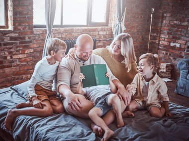 Mutlu çocuklar ve aileleri otelde masal okuyorlar.