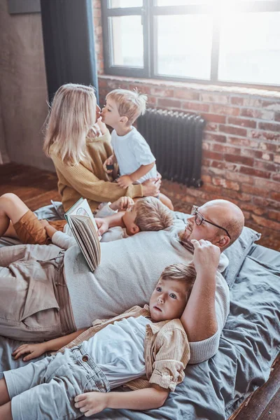 Pais ensinando seus filhos a ler na sala de estar — Fotografia de Stock