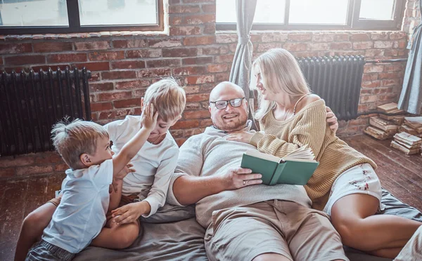 Niños felices y sus padres leyendo cuentos de hadas en el hotel — Foto de Stock
