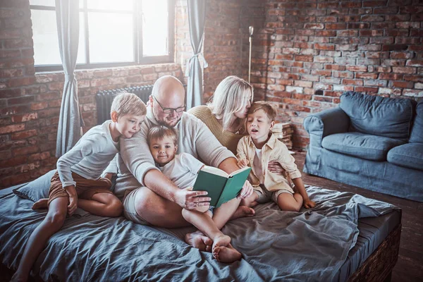 Padres positivos descansando en la sala de estar con sus hijos — Foto de Stock
