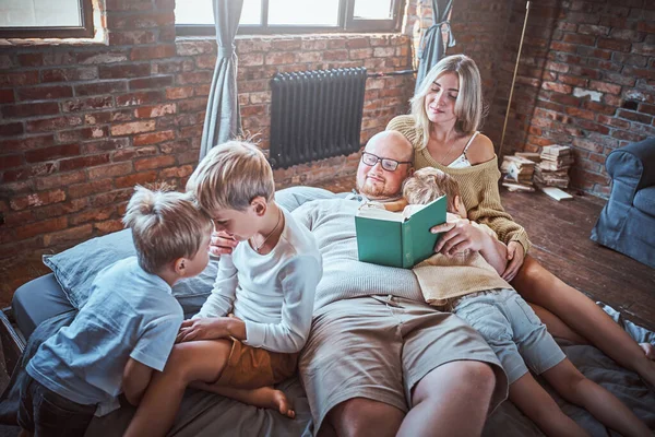 Pais ensinando seus filhos a ler na sala de estar — Fotografia de Stock