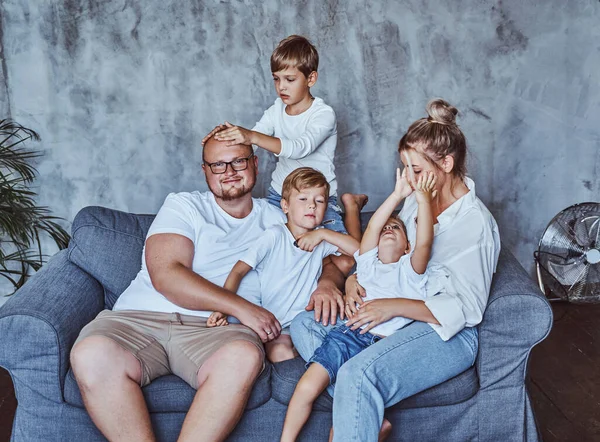 Mãe e pai com seus meninos sentados no sofá — Fotografia de Stock
