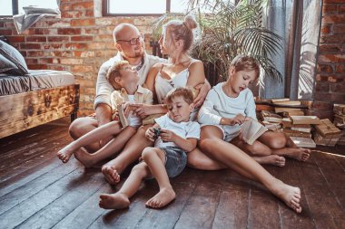 Amerikalı neşeli aile yerde oturup kitap okuyor.