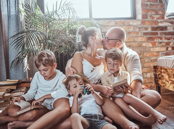Belo casal e seus filhos lendo livros em casa — Fotografia de Stock