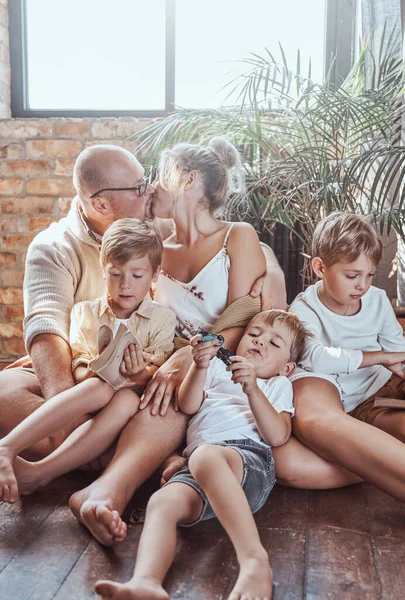 Belo casal e seus filhos lendo livros em casa — Fotografia de Stock