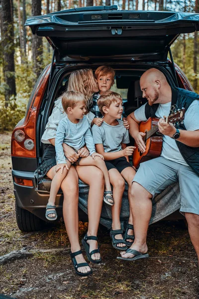 Esposa y marido con sus hijos y coche en el bosque — Foto de Stock