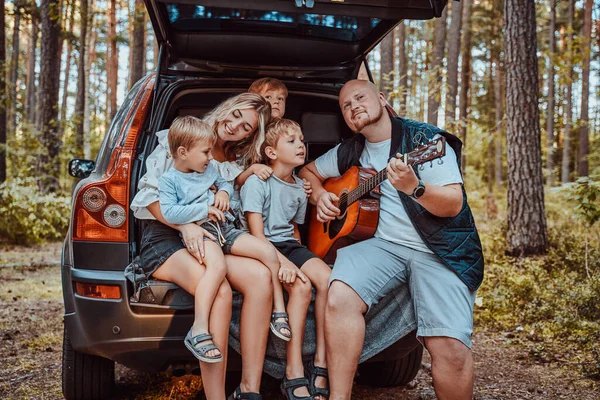 Feliz madre y padre sentados en coche con sus hijos — Foto de Stock