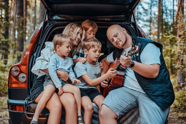 Gelukkig moeder en vader zitten in de auto met hun kinderen — Stockfoto