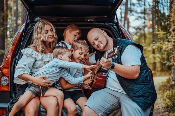 Vrouw en man met hun kinderen en auto in het bos — Stockfoto