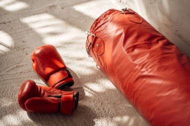 Güneşli oda ve yerde duran kırmızı boks takımları.