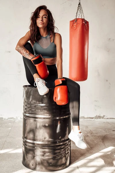 Female boxer sitting on barrel in training room — Stock Photo, Image