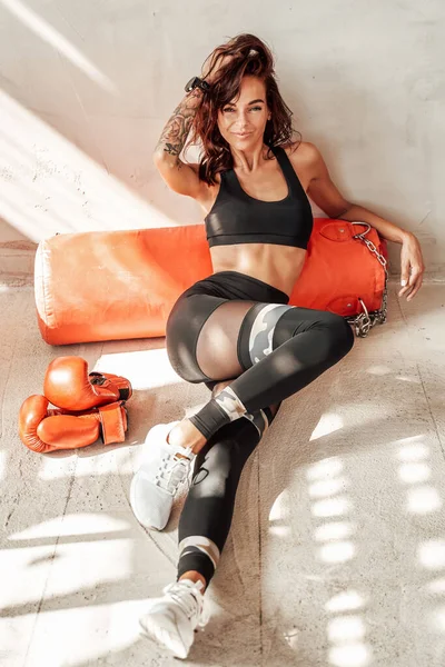 Sportivo femminile in posa vicino alla sua attrezzatura da boxe — Foto Stock
