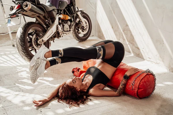 Vrouwelijke bokser en motorrijder liggend op zak — Stockfoto