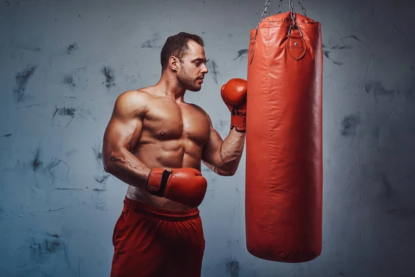 Muskulöser Mann mit nacktem Oberkörper posiert mit Boxsack — Stockfoto