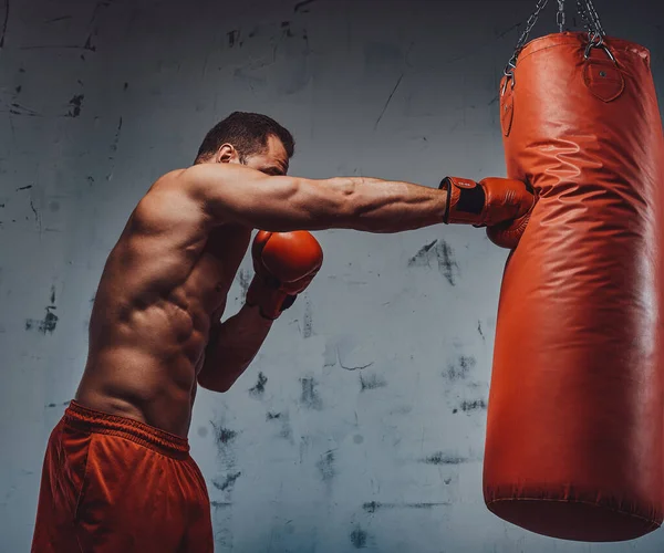 Boxeador con guantes protectores golpeando un saco de boxeo —  Fotos de Stock