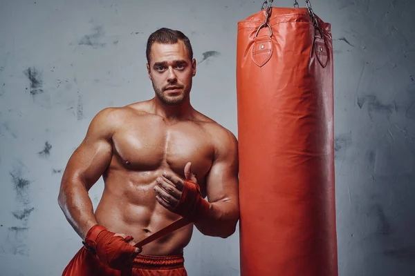 Hombre fuerte con vendajes manos posando alrededor de la bolsa —  Fotos de Stock