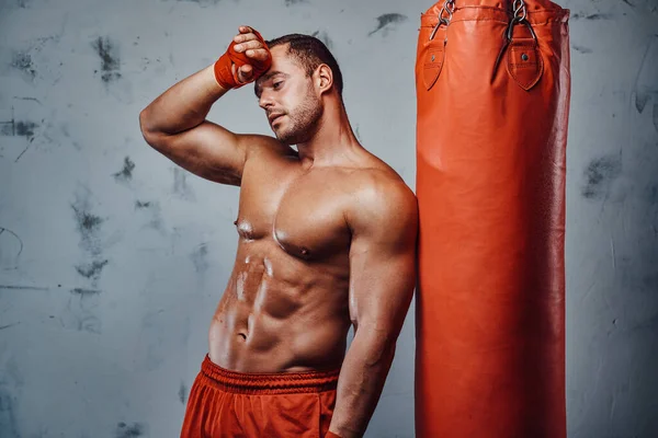 Schöner Boxer ruht sich nach hartem Training in der Nähe der Boxtasche aus — Stockfoto