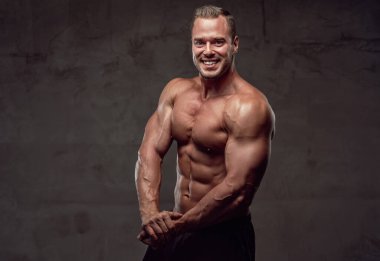 Neşeli vücut geliştirici mükemmel vücudunu stüdyoda gösteriyor.