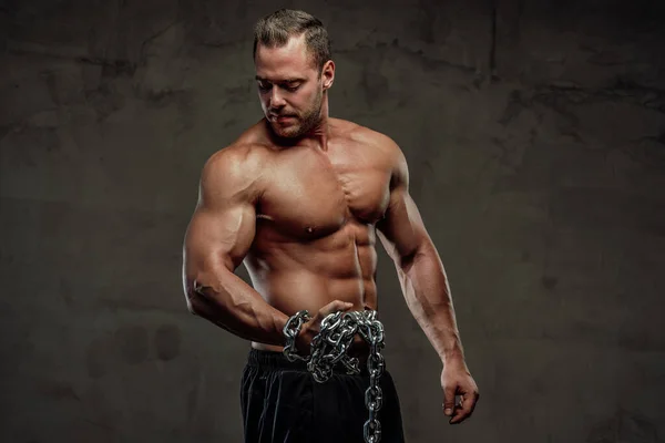 Guy au corps parfait posant avec des chaînes en studio — Photo