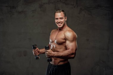 Elinde dambıllarla poz veren güçlü bir adam.