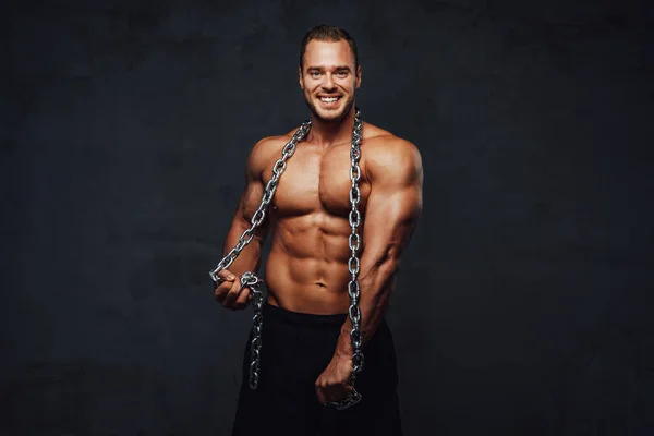 Strong guy with chains posing in special background — Stock Photo, Image