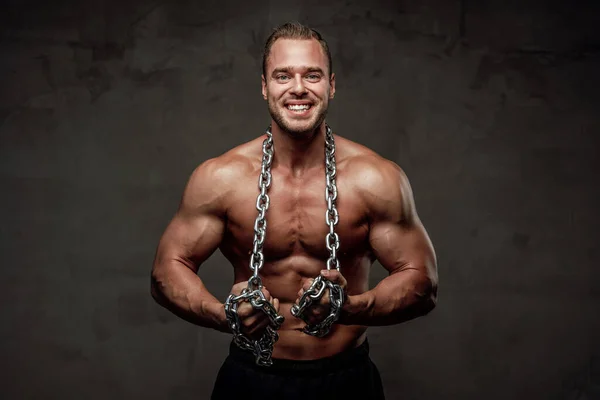 Strong guy with chains posing in special background — Stock Photo, Image