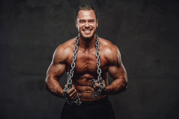 Man med enorma biceps och kedjor poserar i studio — Stockfoto
