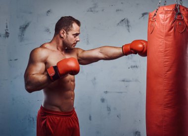 Koruyucu eldivenli boksör kum torbasına vuruyor.