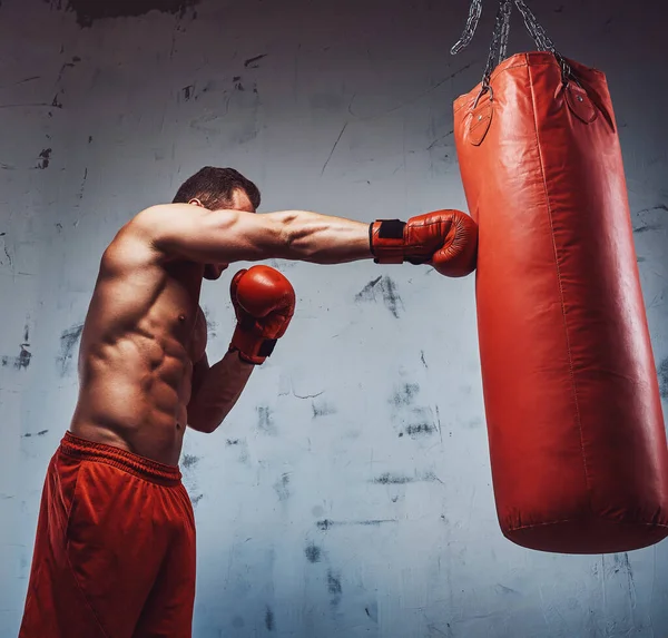 Entrenamiento de culturistas y saco de boxeo con guantes — Foto de Stock