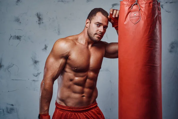 Çıplak gövdeli, kum torbasıyla antrenman yapan kaslı boksör. — Stok fotoğraf