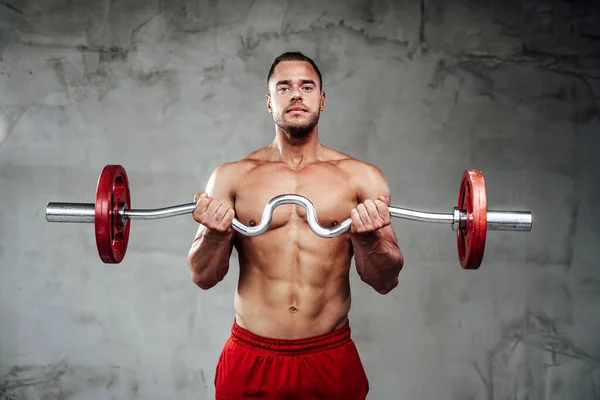 Sportlicher Typ mit muskulösen Händen beim Heben der Langhantel im Hintergrund — Stockfoto