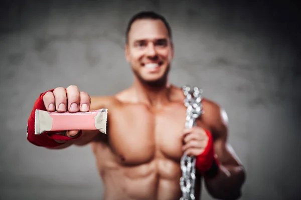 Construtor de corpo feliz mostrando sua barra de proteína favorita — Fotografia de Stock