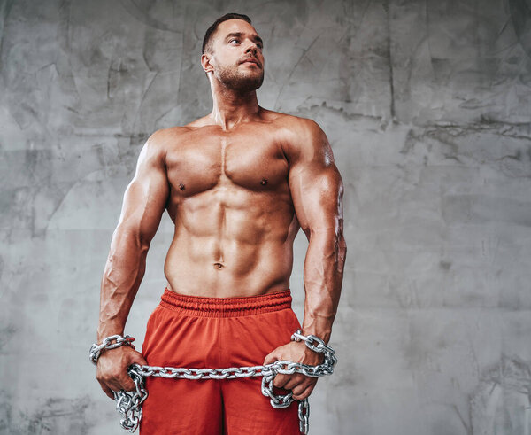 Соблазнительный мускулистый парень с крепкими руками и металлическими цепями