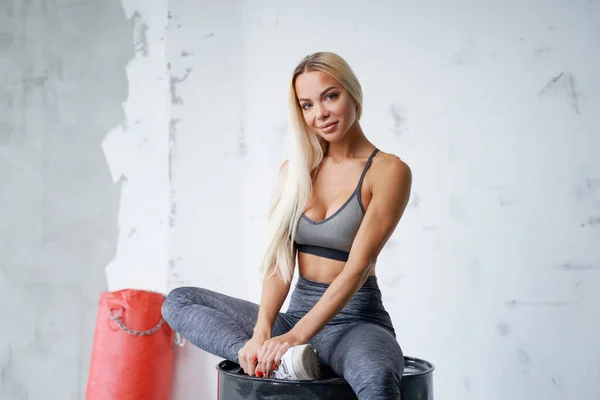 Blondynka ze sportową figurą pozująca na czarnej lufie w studio — Zdjęcie stockowe